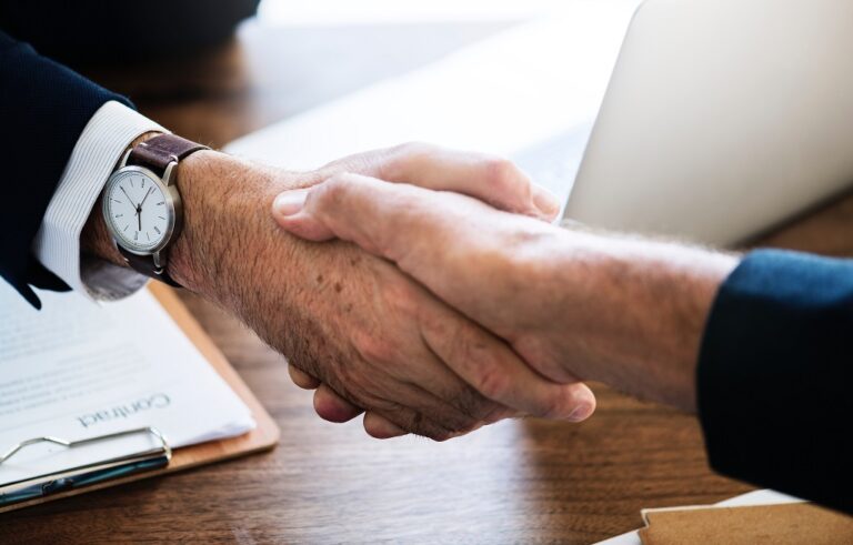 Two bussiness person shaking hands on top of the table